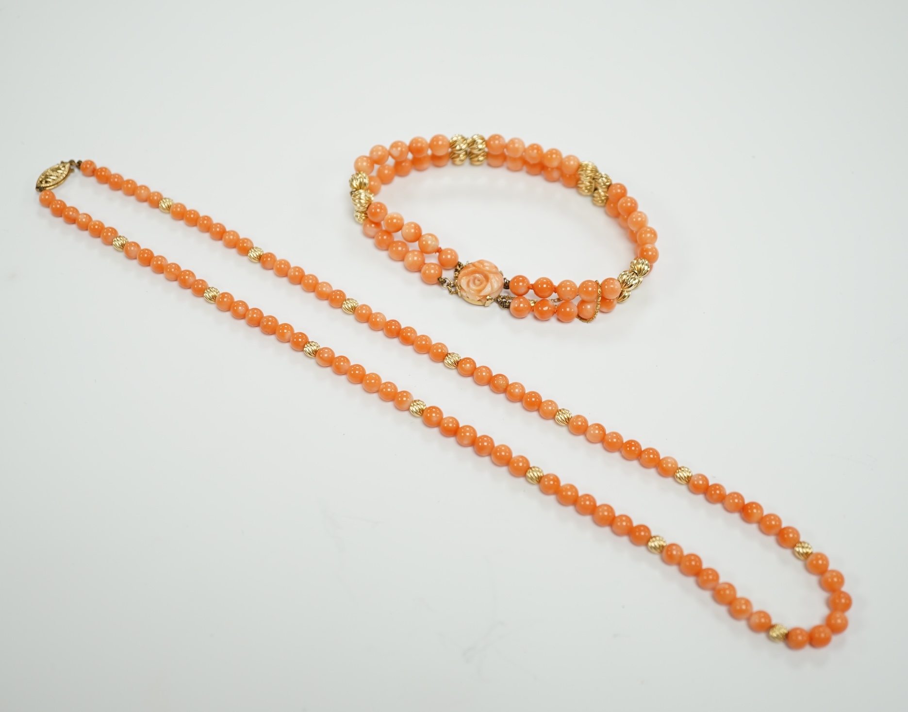 A modern 14k mounted twin strand coral bead necklace, 17cm, together with a 14k mounted single strand coral bead necklace, 44cm.